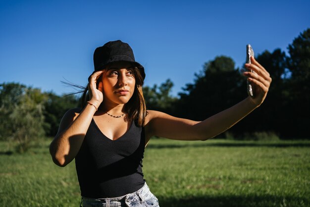 Ritratto di giovane donna che cattura un selfie con uno smartphone in un campo