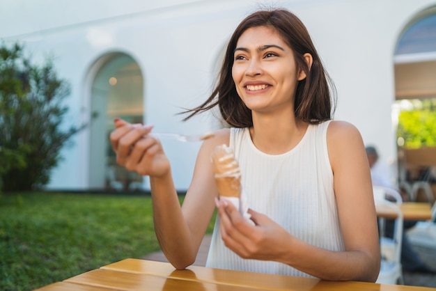 Ritratto di giovane donna che gode del tempo soleggiato mentre mangia un gelato all'aperto. Concetto di stile di vita.