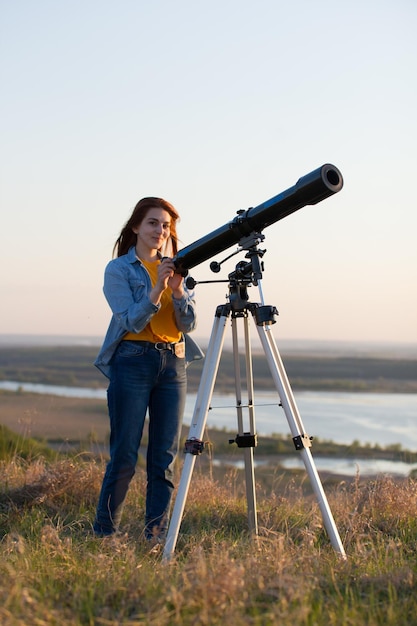 Ritratto di giovane donna che guarda attraverso il telescopio sulla collina da vicino