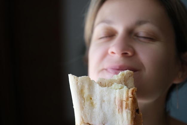 Ritratto di giovane donna che mangia gustoso shawarma squisito spuntino cibo di strada fastfood e cibo da asporto