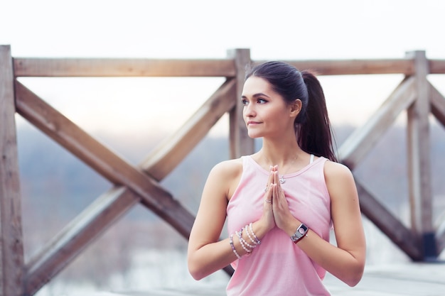 Ritratto di giovane donna che pratica yoga nella posizione del loto all'aperto