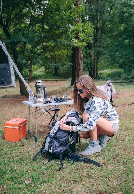 Ritratto di giovane donna che prepara zaino per un'escursione nella foresta