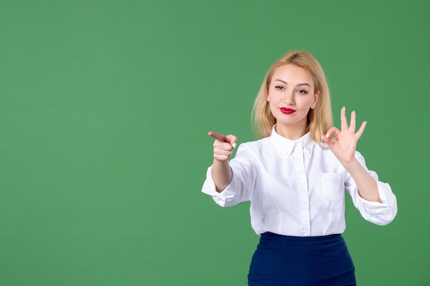 ritratto di giovane donna che punta nel muro verde insegnante studente libro di scuola college