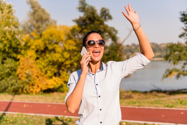 Ritratto di giovane donna che utilizza il telefono cellulare nel parco vicino al fiume