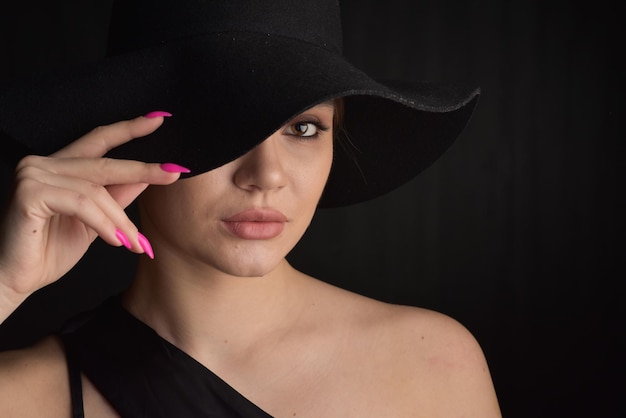 Ritratto di giovane donna con cappello nero e abito da sera