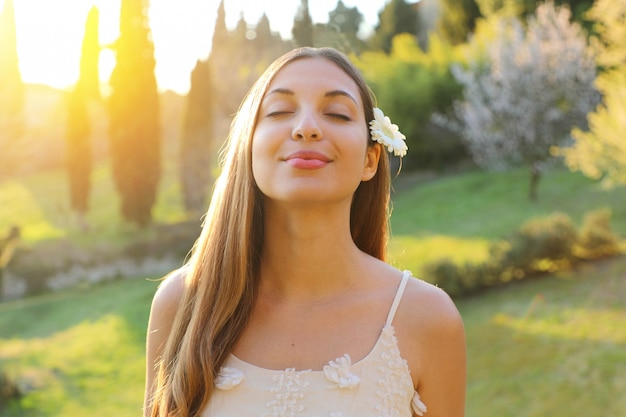 Ritratto di giovane donna con gli occhi chiusi e fiore sull'orecchio