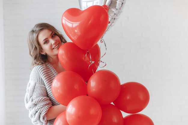 ritratto di giovane donna con palloncini rossi al coperto