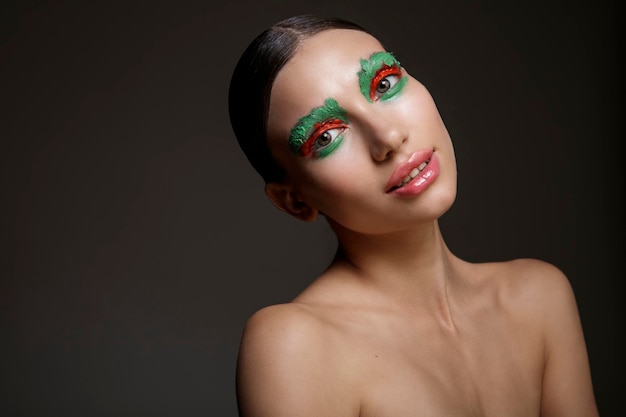 Ritratto di giovane donna con trucco creativo rosso e verde brillante su sfondo scuro Moda di bellezza