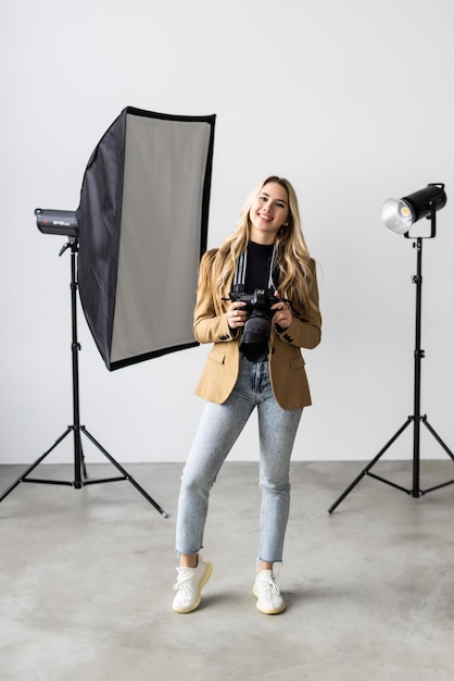 Ritratto di giovane donna con una macchina fotografica in studio con illuminazione sullo sfondo