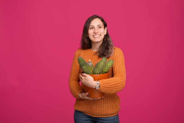 Ritratto di giovane donna felice che tiene una grande pianta di cactus mentre controllando lo spazio del mignolo