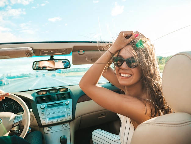 Ritratto di giovane donna hipster bella e sorridente in auto decappottabile