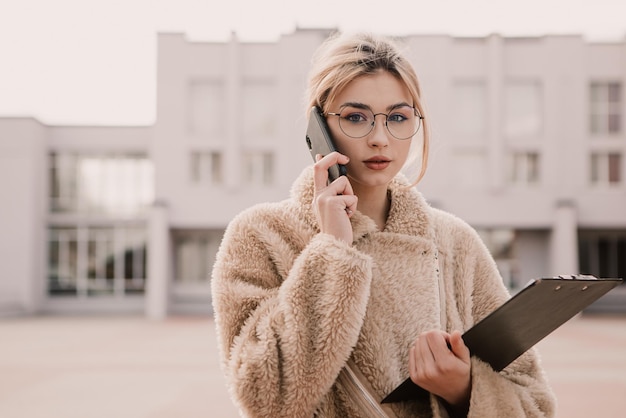 Ritratto di giovane donna hipster indossare occhiali e parlare al telefono
