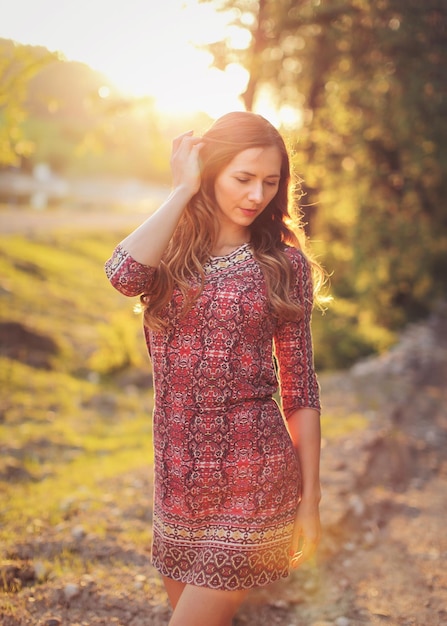 Ritratto di giovane donna in abito estivo casual, forte retroilluminazione al tramonto con un bel bokeh