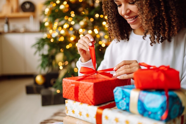 Ritratto di giovane donna in cappello di Babbo Natale con regalo all'albero di Natale Natale Capodanno