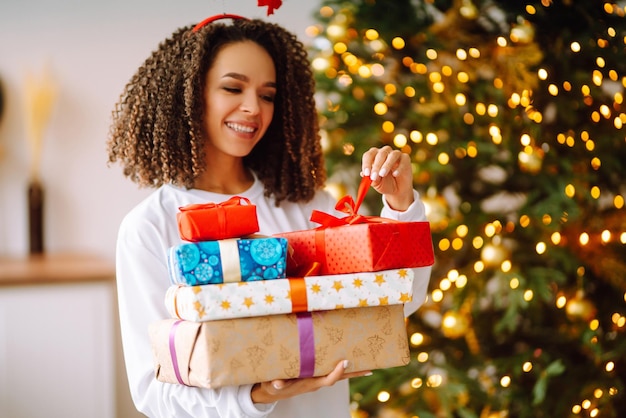 Ritratto di giovane donna in cappello di Babbo Natale con regalo all'albero di Natale Natale Capodanno