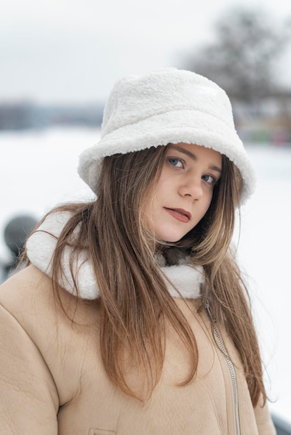 Ritratto di giovane donna in elegante panama di pelliccia bianca fuori nel parco invernale Abbigliamento da donna caldo alla moda