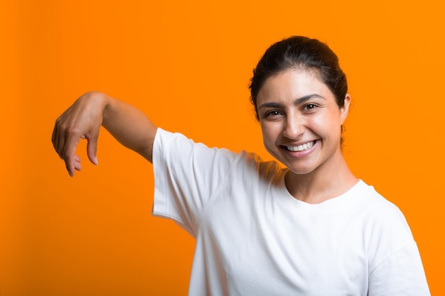 Ritratto di giovane donna indiana adulta sorridente con la mano vuota che tiene qualcosa con le dita. Modello pubblicitario con spazio di copia.