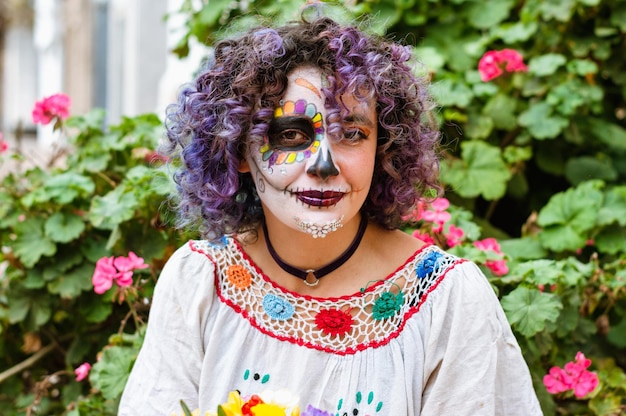 Ritratto di giovane donna latina con trucco La Calavera Catrina con piante e fiori sullo sfondo