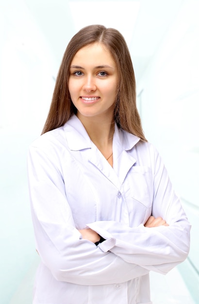 Ritratto di giovane donna medico felice in piedi con le braccia incrociate.