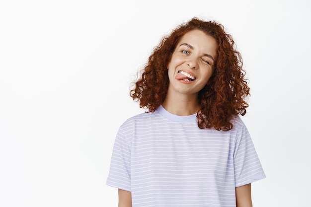 Ritratto di giovane donna positiva e felice con i denti bianchi, che mostra la lingua e sorride in studio.