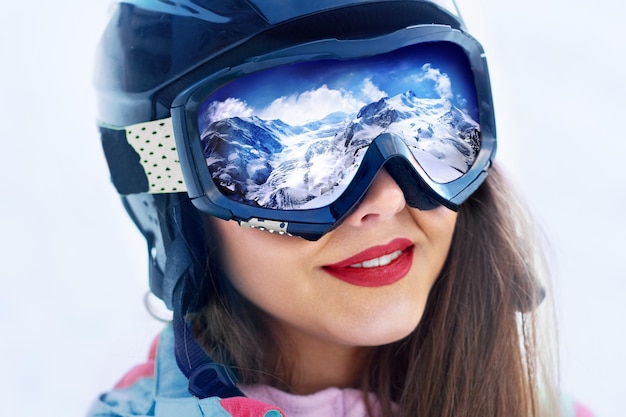 Ritratto di giovane donna presso la stazione sciistica sullo sfondo di montagne e cielo blu