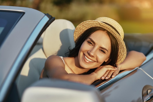 Ritratto di giovane donna seduta in cabrio e guardando la telecamera