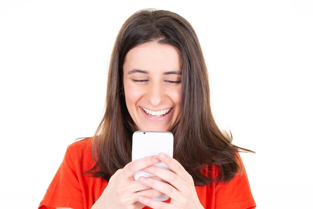 Ritratto di giovane donna sorridente capelli castani che manda un sms sullo smartphone con la felicità del sorriso sul telefono