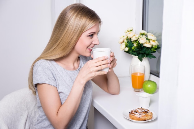 Ritratto di giovane donna sorridente che fa colazione a casa