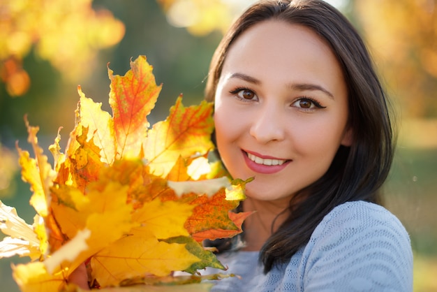 Ritratto di giovane donna sorridente con foglie di autunno