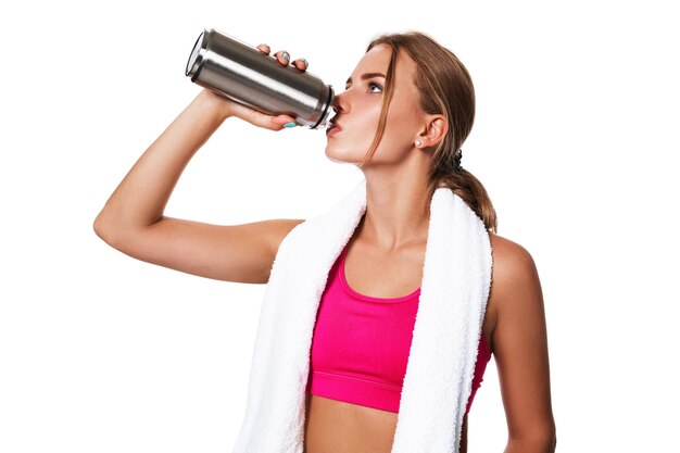 Ritratto di giovane donna sportiva stanca dopo un allenamento in palestra. Donna con un asciugamano bianco e una bottiglia d'acqua isolata su sfondo bianco