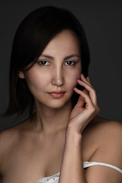 Ritratto di giovane e bella donna asiatica sul muro grigio