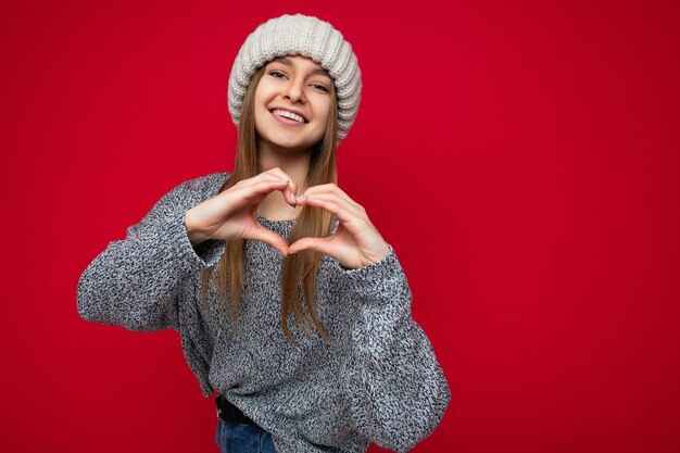 Ritratto di giovane e bella donna bionda scura sorridente positiva con emozioni sincere che indossano grigio