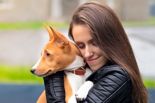 Ritratto di giovane e bella donna che abbraccia il suo cane purosangue basenji congo terrier