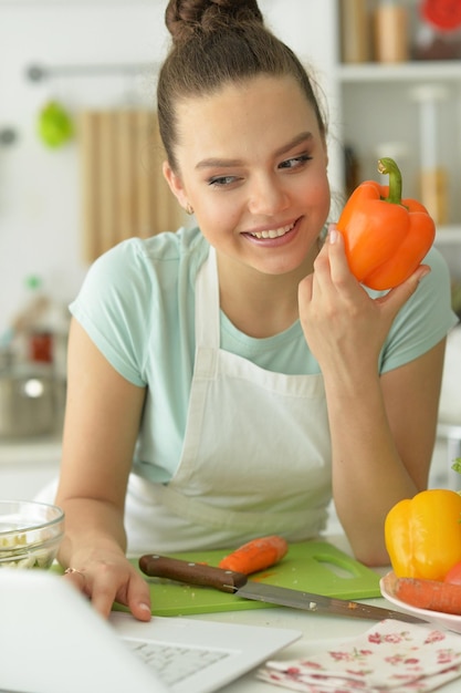 Ritratto di giovane e bella donna che fa insalata in cucina