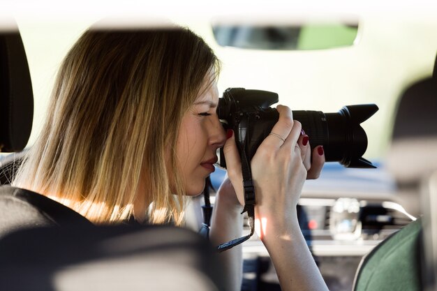 Ritratto di giovane e bella donna che scatta foto dall'auto.