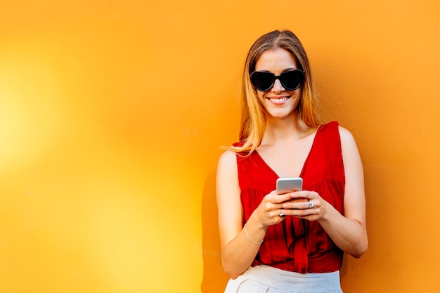 Ritratto di giovane e bella donna che utilizza il telefono cellulare in strada. Concetto di telefonia mobile.