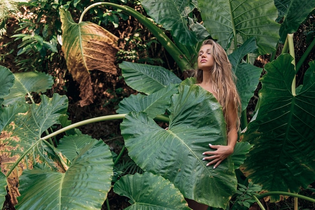 Ritratto di giovane e bella donna con perfetta pelle liscia e capelli lunghi in foglie tropicali. di cosmetici naturali e cura della pelle. -