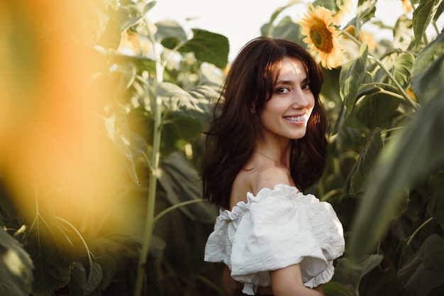 Ritratto di giovane e bella donna in un campo di girasoli