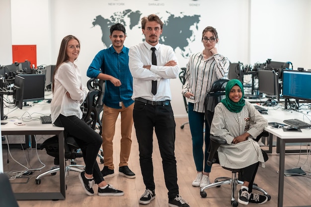 Ritratto di giovane eccitato team aziendale multietnico di sviluppatori di software in piedi e guardando la telecamera in un moderno ufficio di avvio. Foto di alta qualità