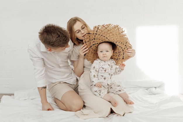 Ritratto di giovane famiglia sorridente felice in abiti bianchi con un piccolo bambino paffuto dagli occhi azzurri infa