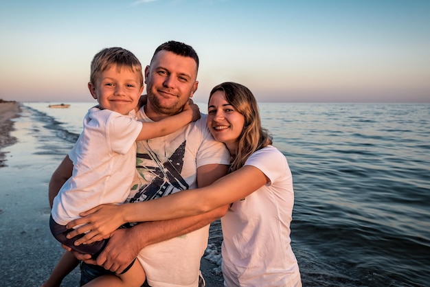 Ritratto di giovane famiglia sulla spiaggia al tramonto