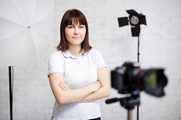 Ritratto di giovane fotografo femminile in posa con la macchina fotografica e torce elettriche in studio