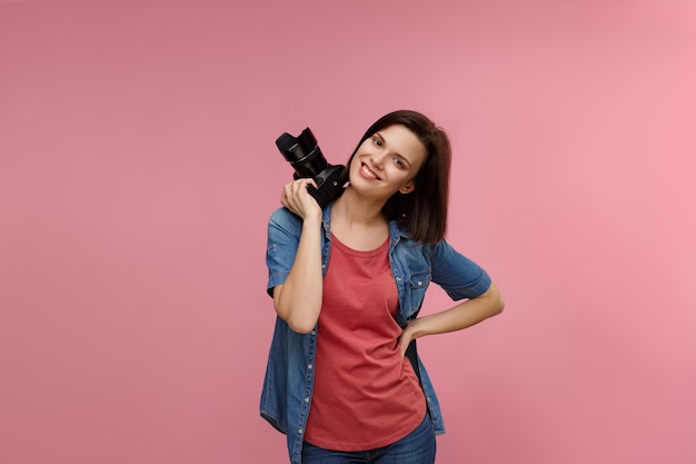 Ritratto di giovane fotografo femminile isolato su sfondo rosa con spazio di copia.