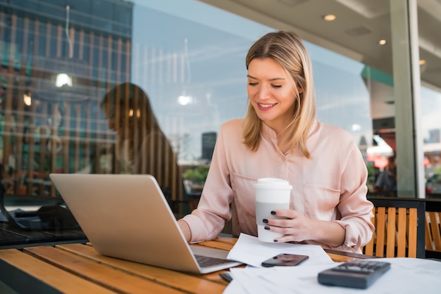 Ritratto di giovane imprenditrice lavorando sul suo computer portatile in una caffetteria. Concetto di affari.