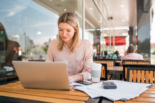 Ritratto di giovane imprenditrice lavorando sul suo computer portatile in una caffetteria. Concetto di affari.