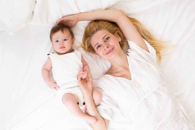 Ritratto di giovane madre con i capelli biondi con la sua dolce bambina di 3 mesi