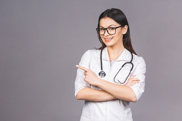 Ritratto di giovane medico femminile allegro con lo stetoscopio sopra il collo che indica dito.