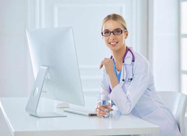 Ritratto di giovane medico femminile seduto alla scrivania in ospedale