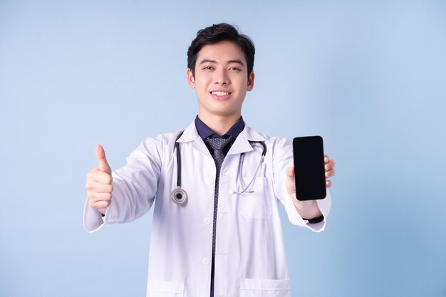 Ritratto di giovane medico maschio asiatico su sfondo blu