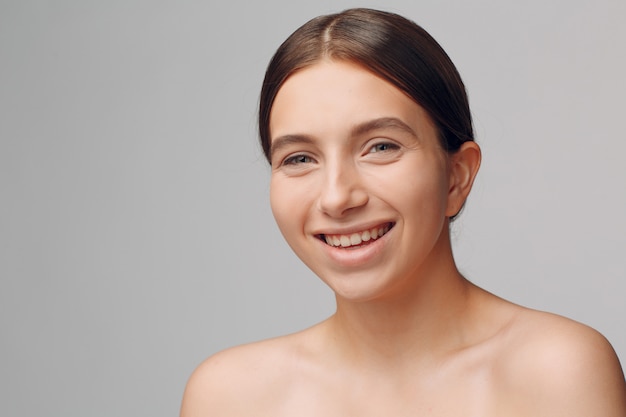 Ritratto di giovane modello sorridente della donna in studio con trucco naturale. Concetto di trucco.